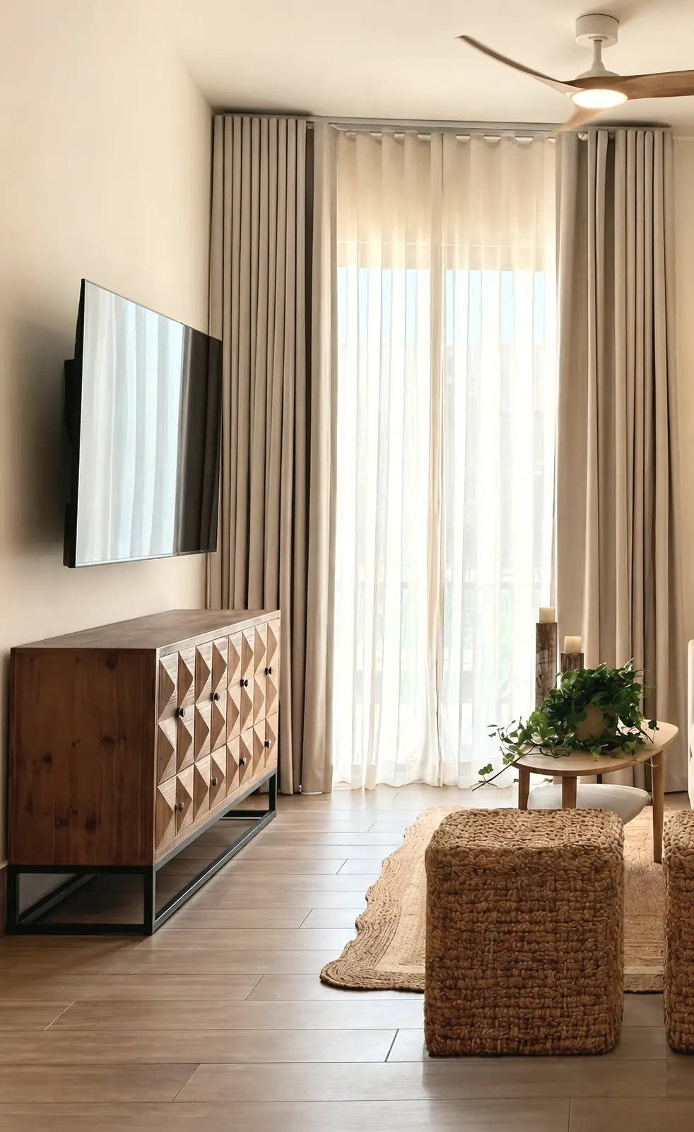 Sala con credenza de madera tallada, pufs de fibra y cortinas de lino
